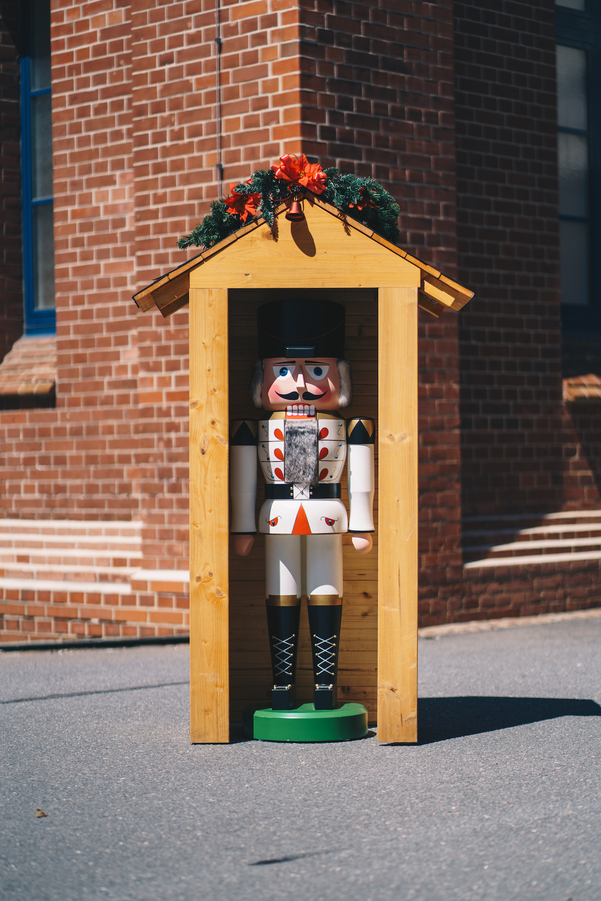 A very big nutcracker (large figure from the Ore Mountains) stands in a small wooden house decorated with Christmas decoration.