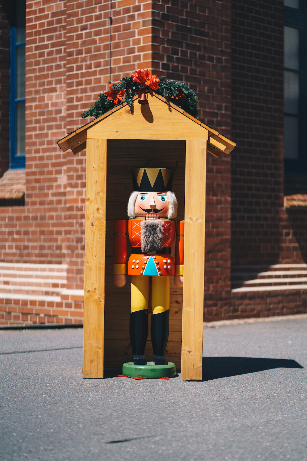 A very big nutcracker (large figure from the Ore Mountains) stands in a small wooden house decorated with Christmas decoration.